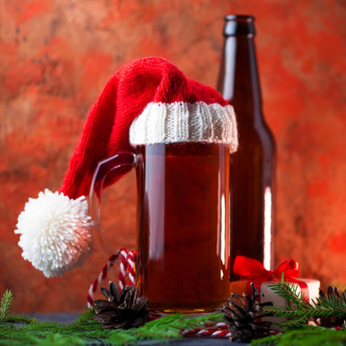 Christmas beer in a glass with a Santa hat on top and a bottle of beer