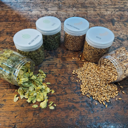 Hops and malts in containers displayed on an oak table